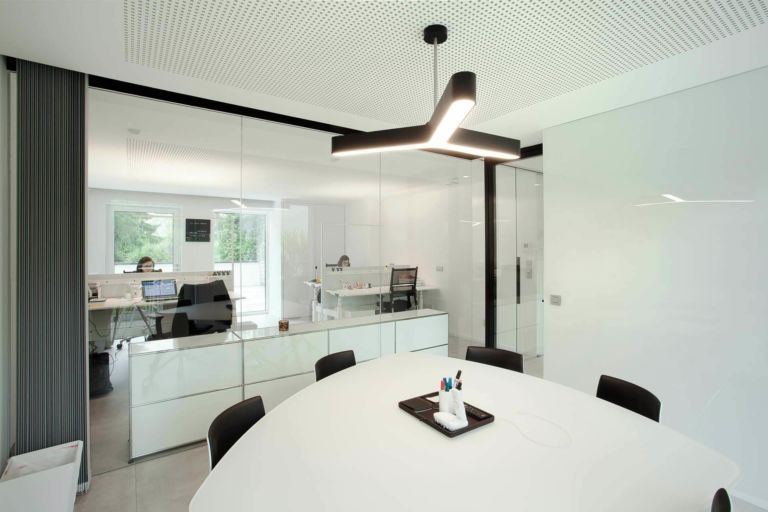 salle de réunion du bureau Cat2Lion. Table ronde permettant proximité et facilité d'échanges. Le blanc et le noir créent une ambiance sobre et moderne. Les différents espaces sont séparés par des cloisons vitrées pour préserver le plus de lumière possible.